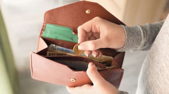 woman pulling pocket change out of brown pocketbook