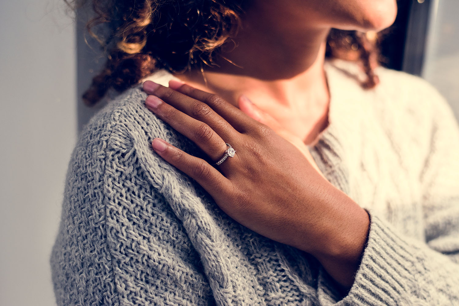 A smiling woman with her hand, wearing an engagement ring, on her shoulder